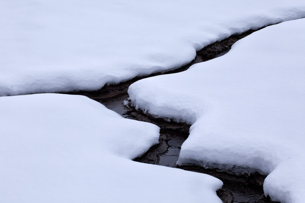 Abstract of a small stream cutting through the snow in Wyoming