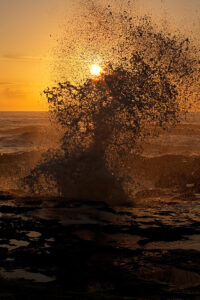 Ocean wave splash backlit by setting sun