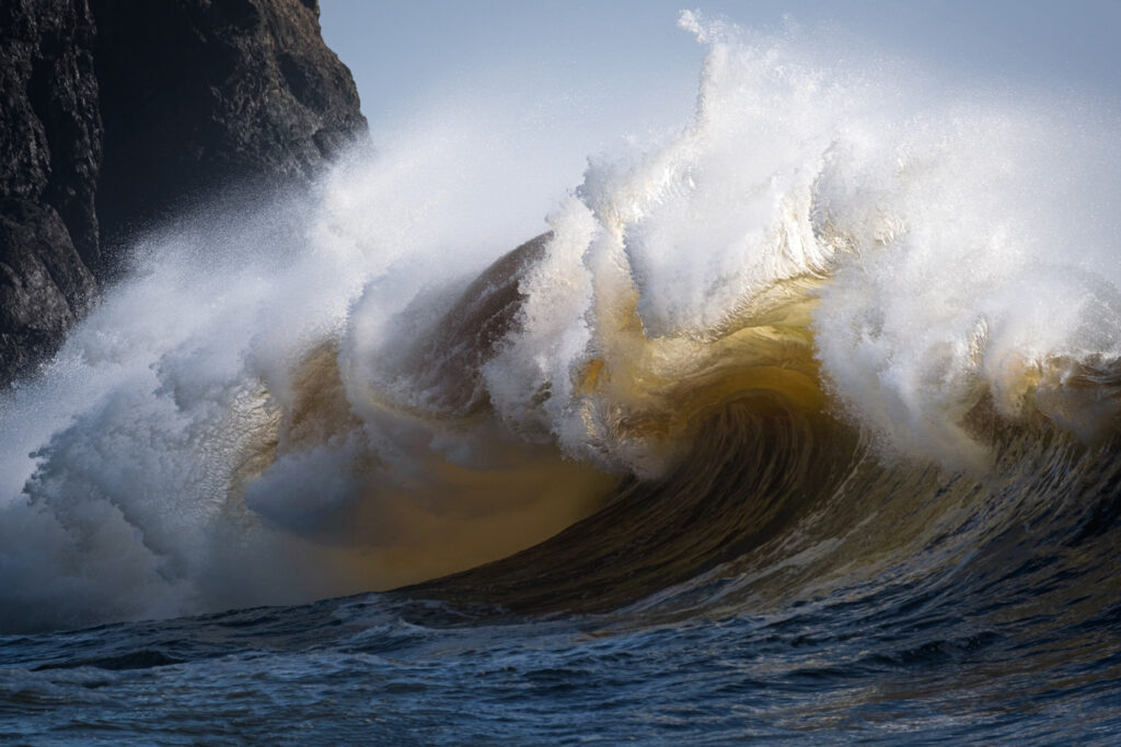A giant waves curls up and crashes along the Washington coastline