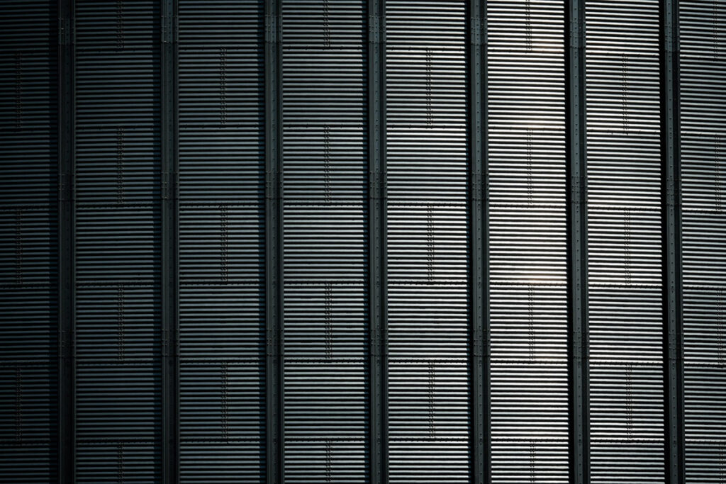 The side of a large grain silo reflecting the sunlight
