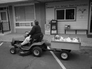 A grandma drove riding lawnmower with grandchild in back to store for groceries