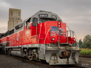 A red train sits in front of grain silo in the Palouse area of Eastern Washington