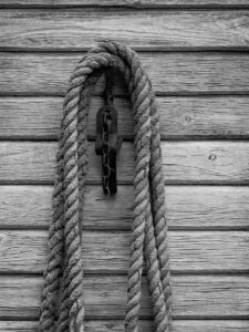 A rope hangs against a wooden wall in monochrome