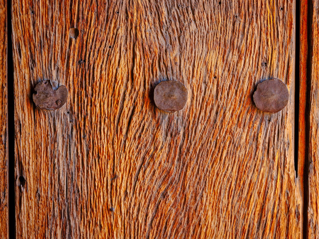 Weathered wood with three rusty nails