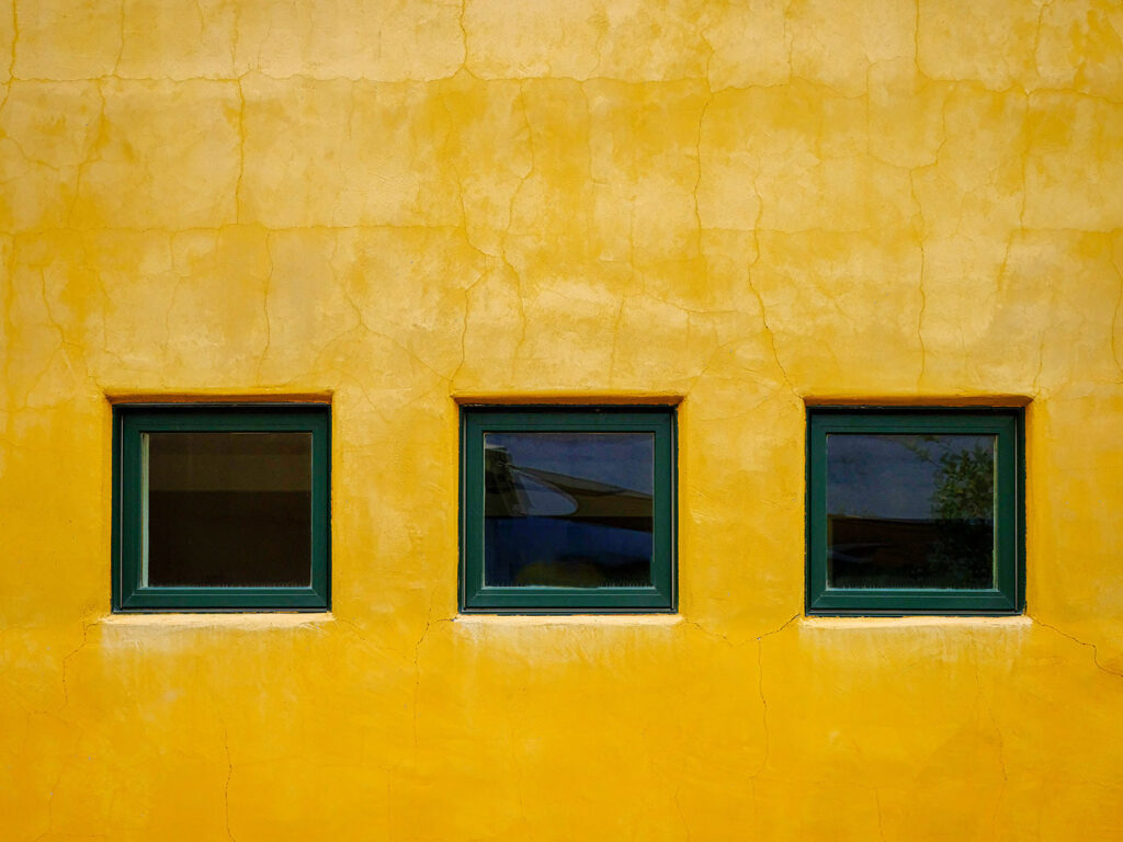 3 square windows set in the side of a yellow wall in Arizona