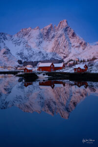 Sunrise in Balstad Norway with red houses and a reflection on the water.