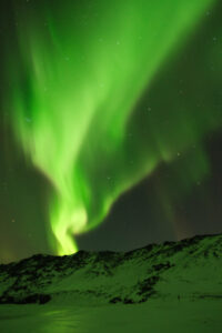 the northern lights erupt over a mountain in Iceland
