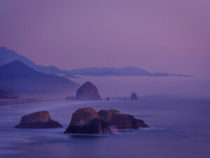 Sea stacks in the ocean near Canon Beach Oregon with pastel pink sky