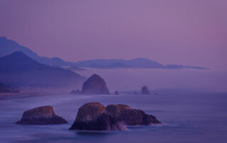 Sea stacks in the ocean near Canon Beach Oregon with pastel pink sky