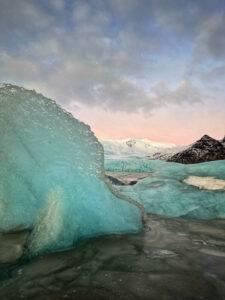 The serrated edge of an iceberg points towards a distant mountain in Iceland