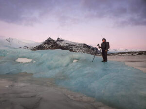 John Pedersen stands on a iceberg to compose a photograph in Iceland