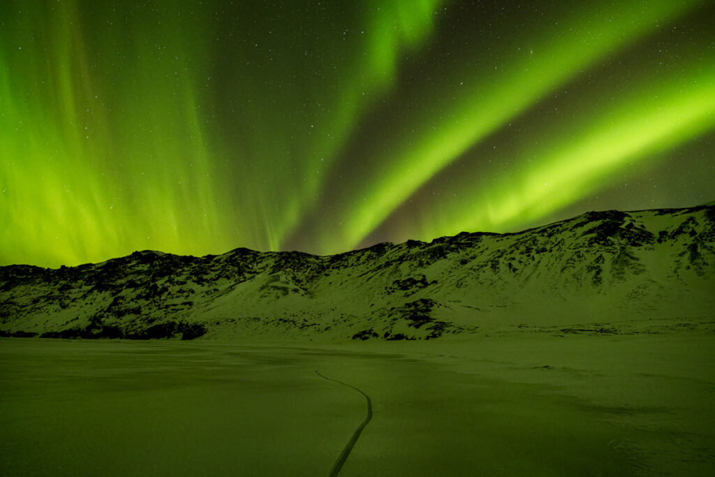 The northern lights over snowy mountains during winter in Iceland