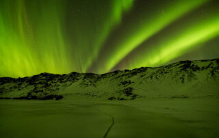 The northern lights over snowy mountains during winter in Iceland