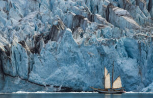 A sailing boat against the face of a glacier in Greenland