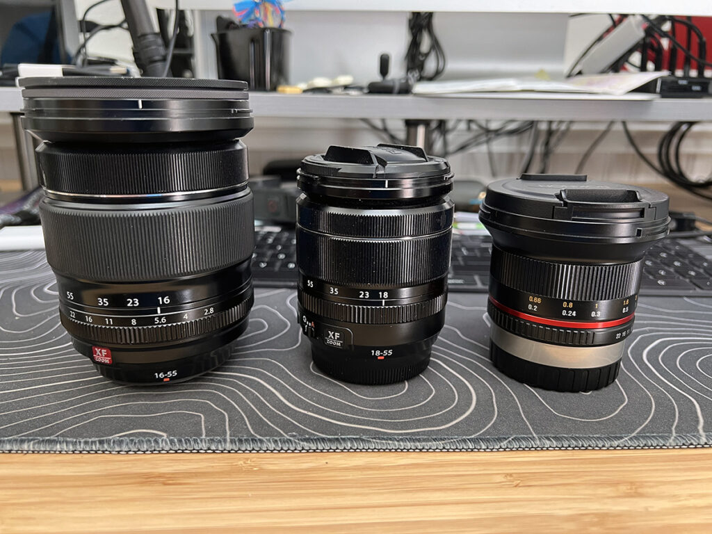 The Rokinon 12mm f/2 next to the Fujifilm 18-55 and 16-55 lenses