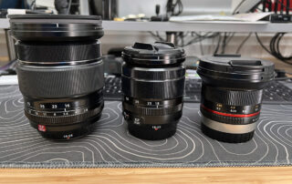 The Rokinon 12mm f/2 next to the Fujifilm 18-55 and 16-55 lenses