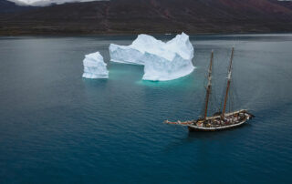 A giant iceberg and wooden sailing ship in Greenland