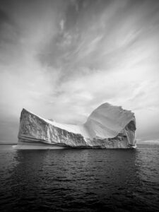 An iceberg under cloudy skies in the fjords of Greenland